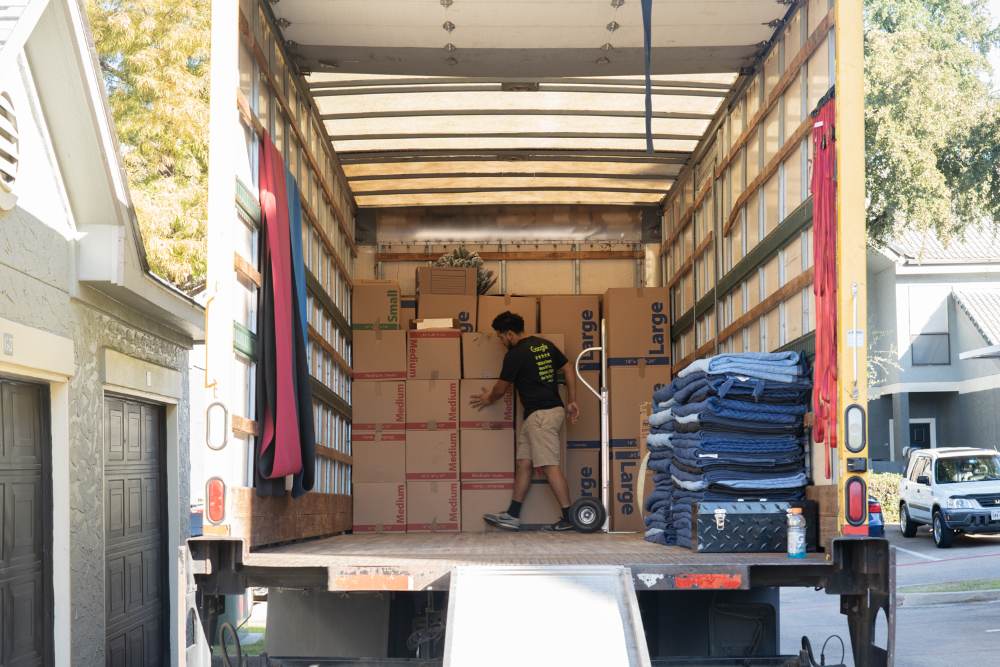 AAA Pro Movers crew member loading labeled boxes with moving blankets on hand
