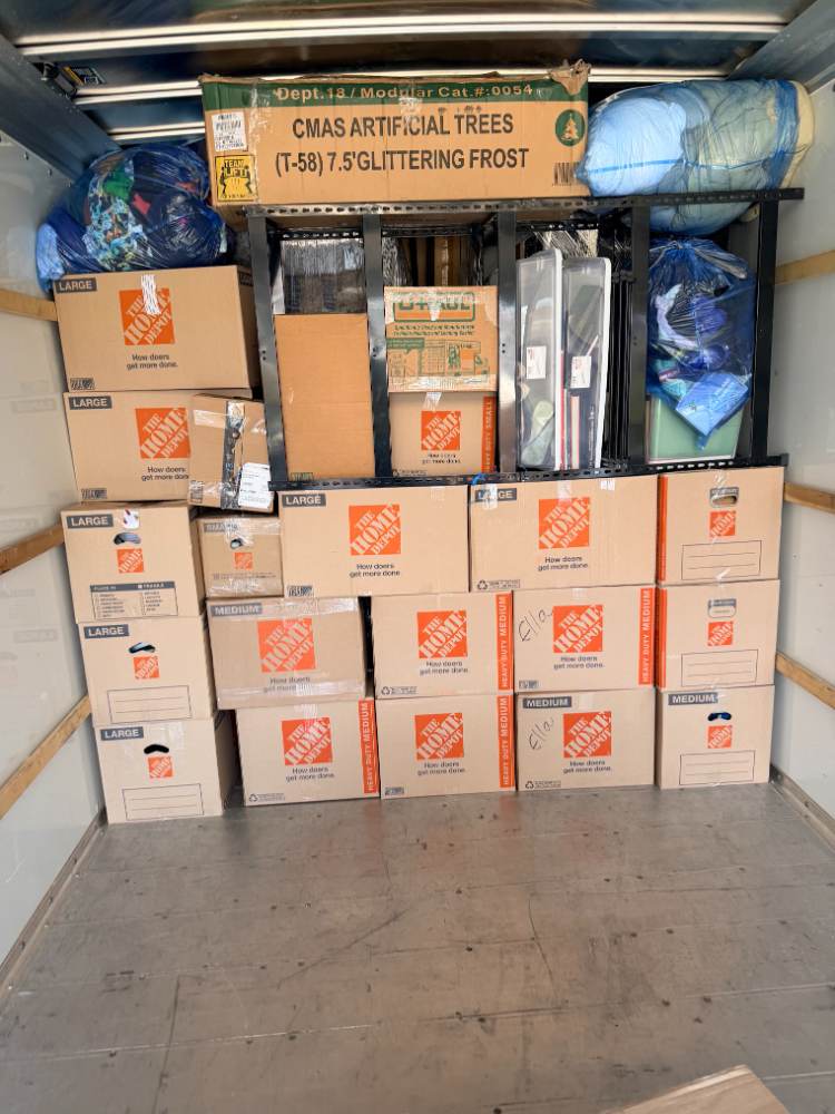 Movers using a hand truck to load boxes during a residential move